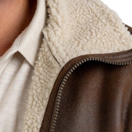 Close-up of a brown leather jacket with a white fleece lining.